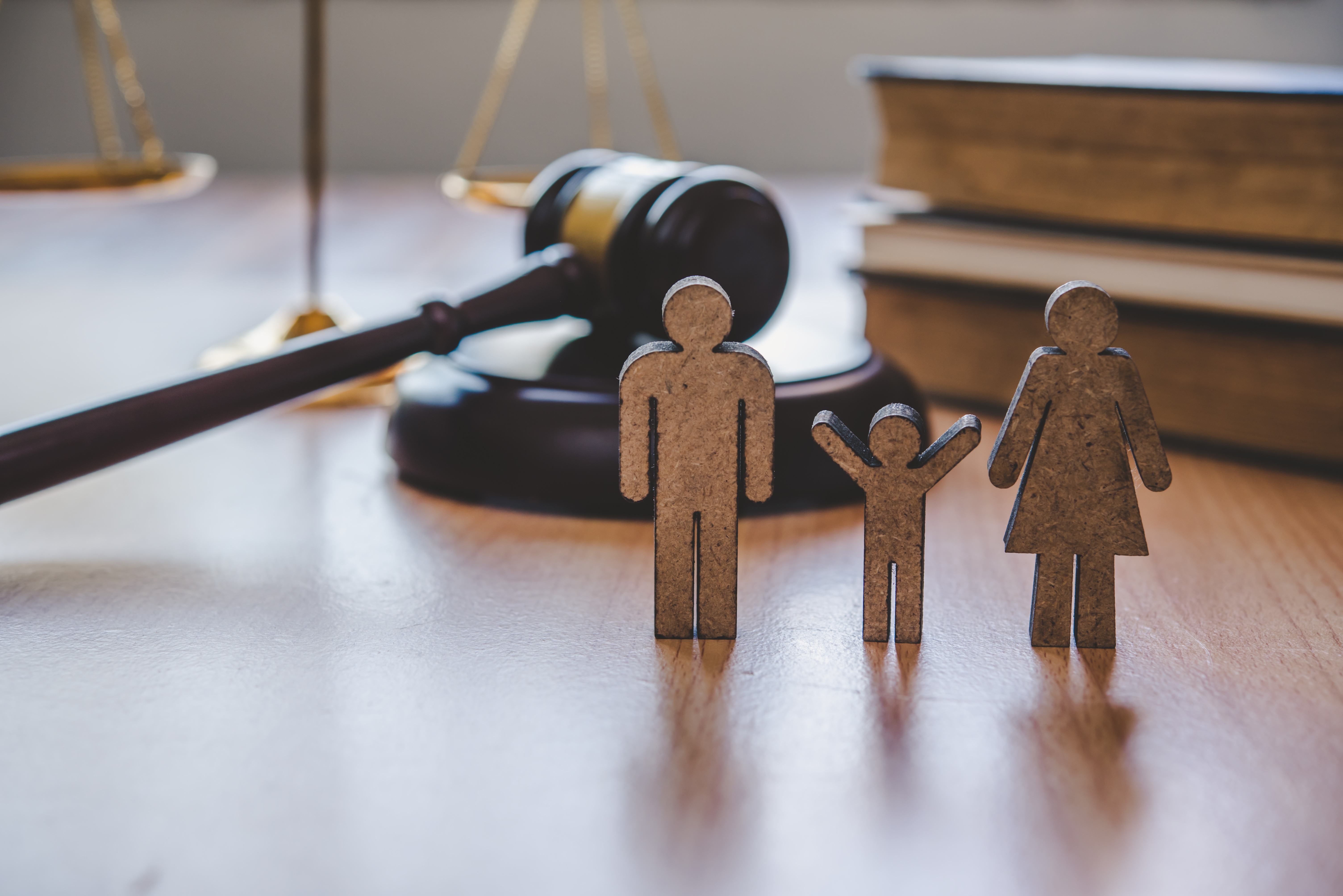 Holzfiguren einer Familie vor einem Richterhammer - Symbol für internationales Familienrecht