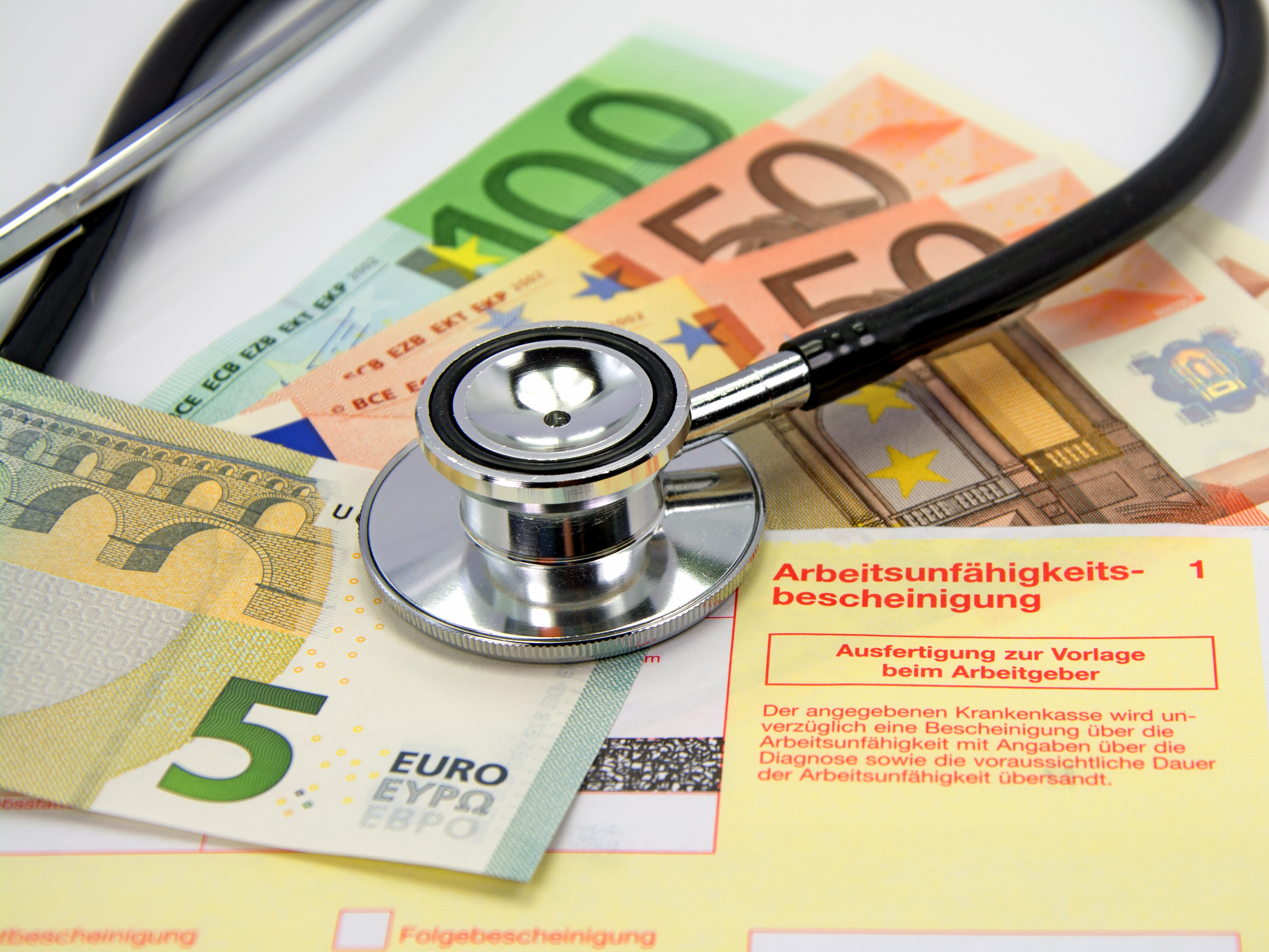 Arbeitsunfähigkeitsbescheinigung mit Stethoskop und Euro-Scheinen